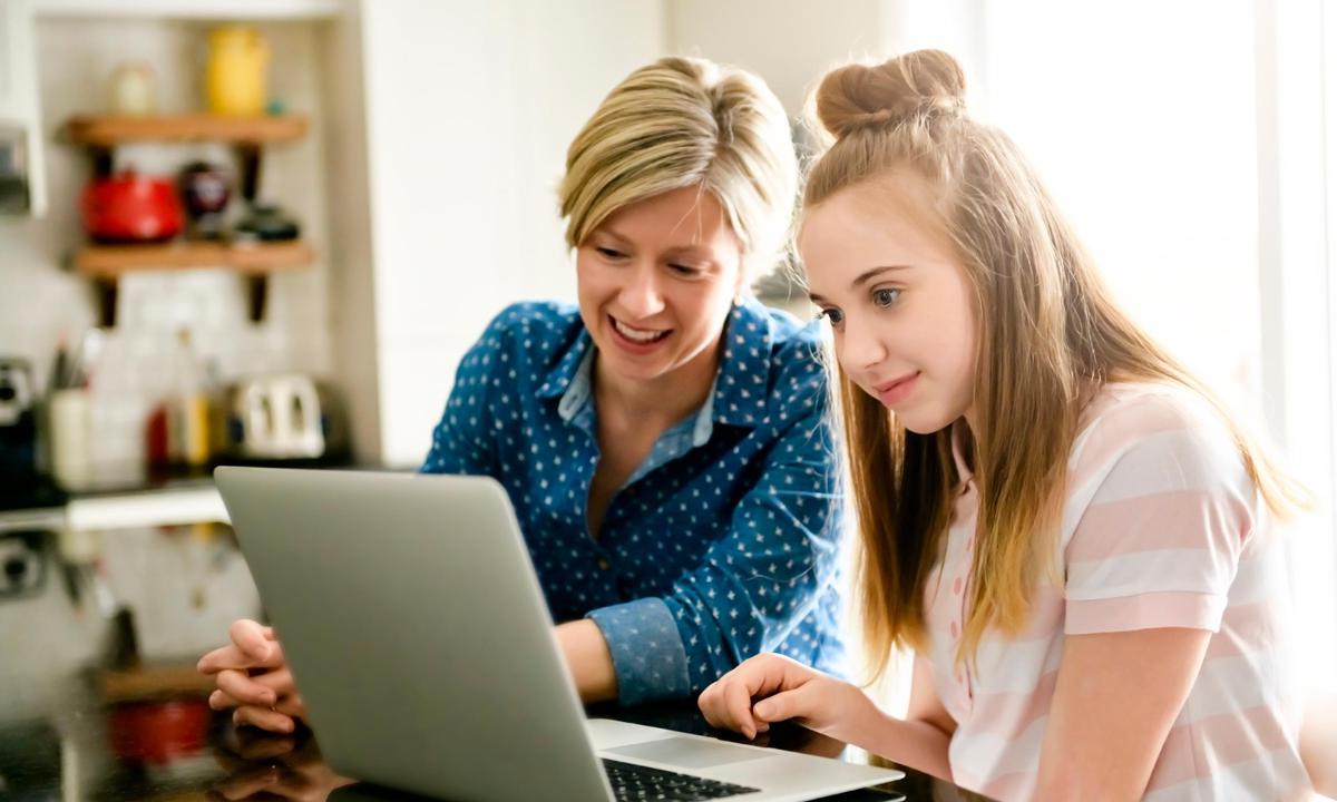 Adolescente viendo el ordenador con su madre