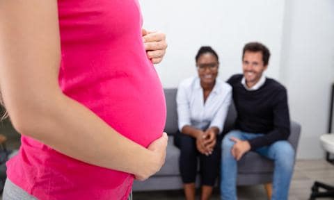 Pregnant Woman In Front Of Couple Sitting On Sofa