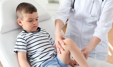 Médico explorando a un niño con dolor de rodilla