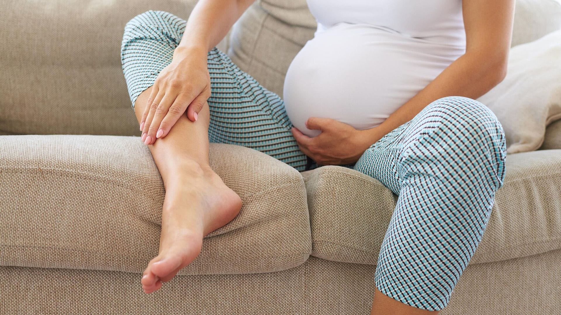 Mujer embarazada tocándose las piernas