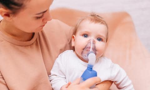 Bebé con un nebulizador con su madre