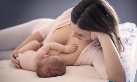 Madre dando el pecho a su bebé acostada