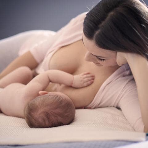 Madre dando el pecho a su bebé acostada
