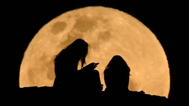Girls from Queenscliff watch the rising full moon at Manly Beach in Sydney on September 18, 2024.