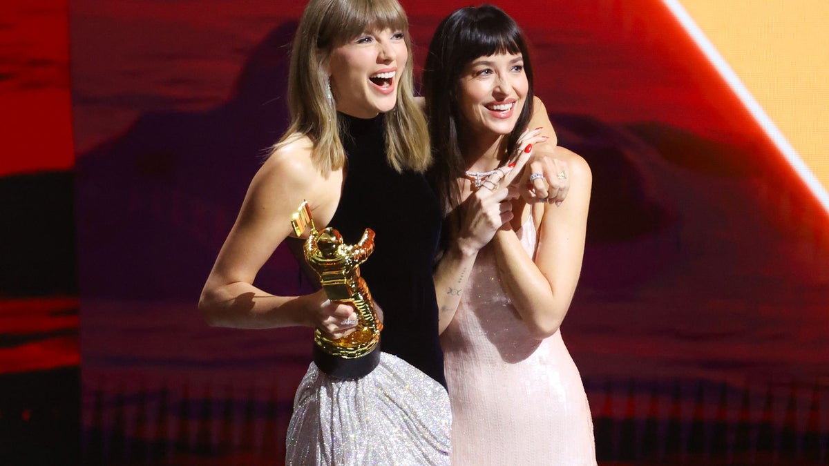 https://www.hola.com/us/horizon/landscape/1200/06576672949e-taylor-swift-and-dakota-johnson-onstage-as-swift-accepts-the-artist-director-hon.jpg