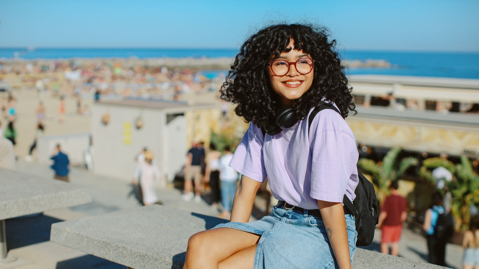https://www.hola.com/us/horizon/landscape/1e52f73acc41-una-joven-de-pelo-rizado-estc3a1-sentada-en-un-banco-con-las-piernas-cruzadas-.jpg?im=Resize=(1200)