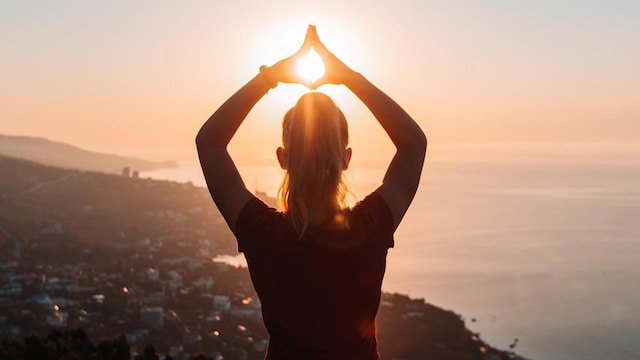 Silhouette of woman doing yoga at sunrise. Harmony, tranquility and relaxation in nature