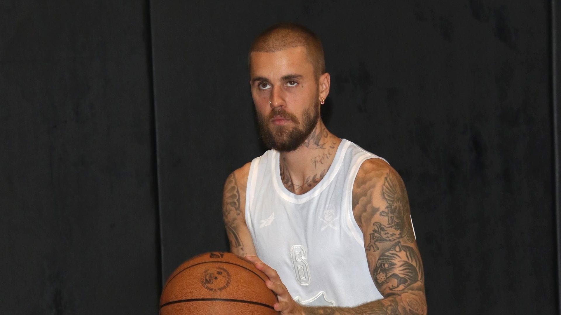 
Justin Bieber is spotted playing basketball at The League in Los Angeles. He is dressed in a white tank top, matching shorts, and colorful sneakers, showcasing his sporty side. 