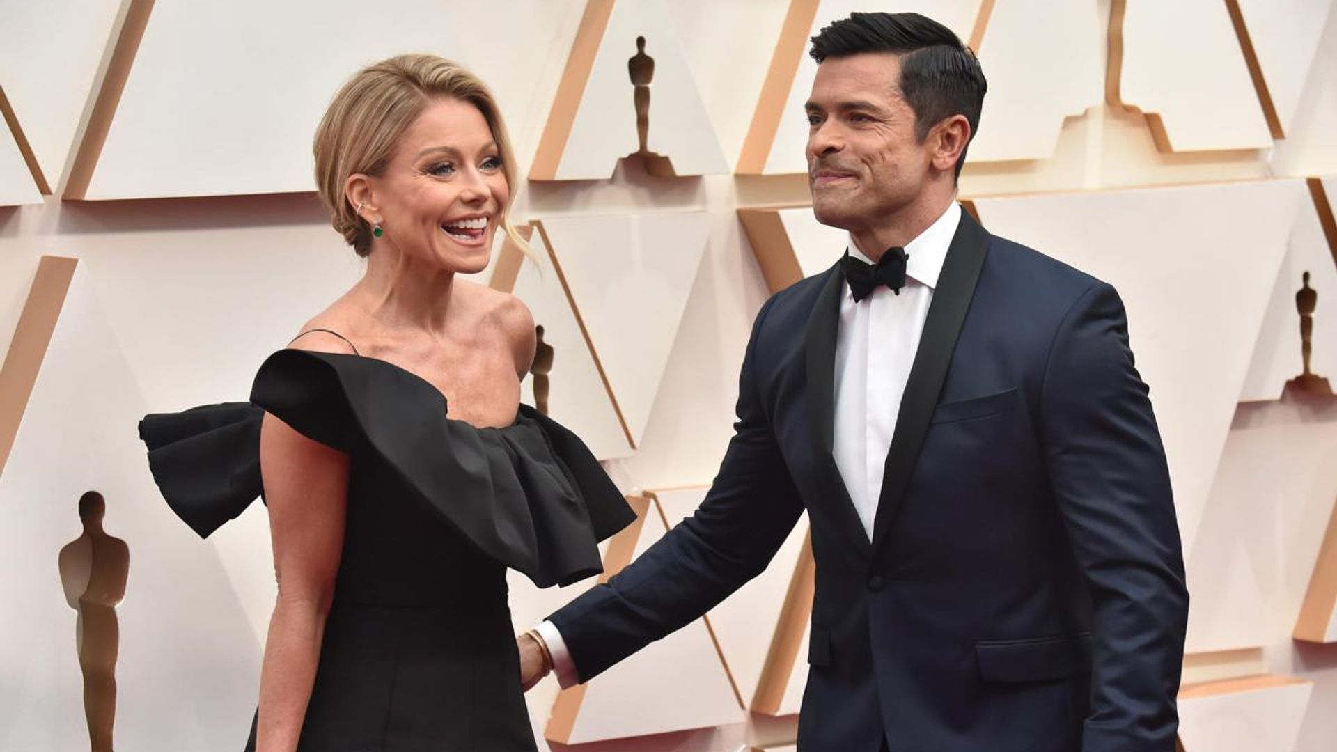 Kelly Ripa and Mark Consuelos explain how they can hold hands despite their arm’s length
