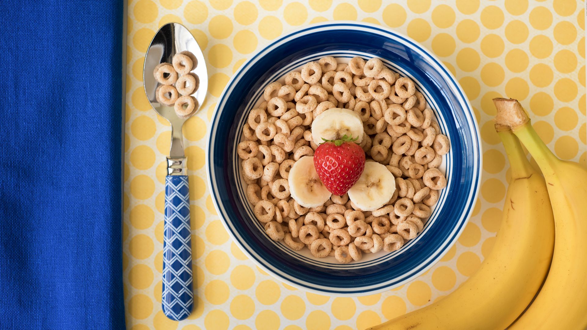 A bowl of cheerios with strawberries and bananas. 