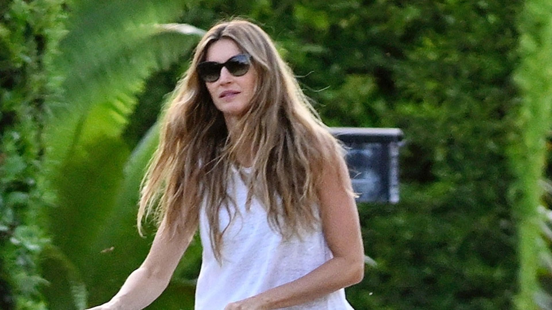 Dressed in a breezy white sleeveless top and matching pants, Gisele looked radiant as she pushed a stroller and played with her dog during the outing. 