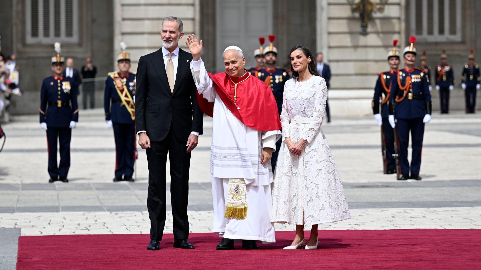 Queen Letizia is wearing a white lace dress while greeting Pope Leo XIV during his official visit to Spain at Madrid-Barajas Airport.