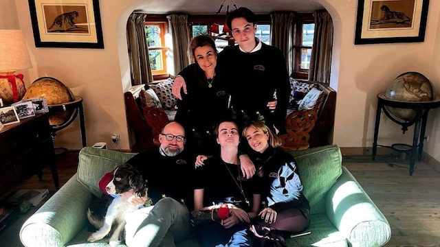 Robert of Luxembourg with his family, sitting together in a warmly lit living room, accompanied by their pet dog.