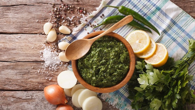 Green spicy sauce chimichurri and ingredients close-up on the table. horizontal view from above