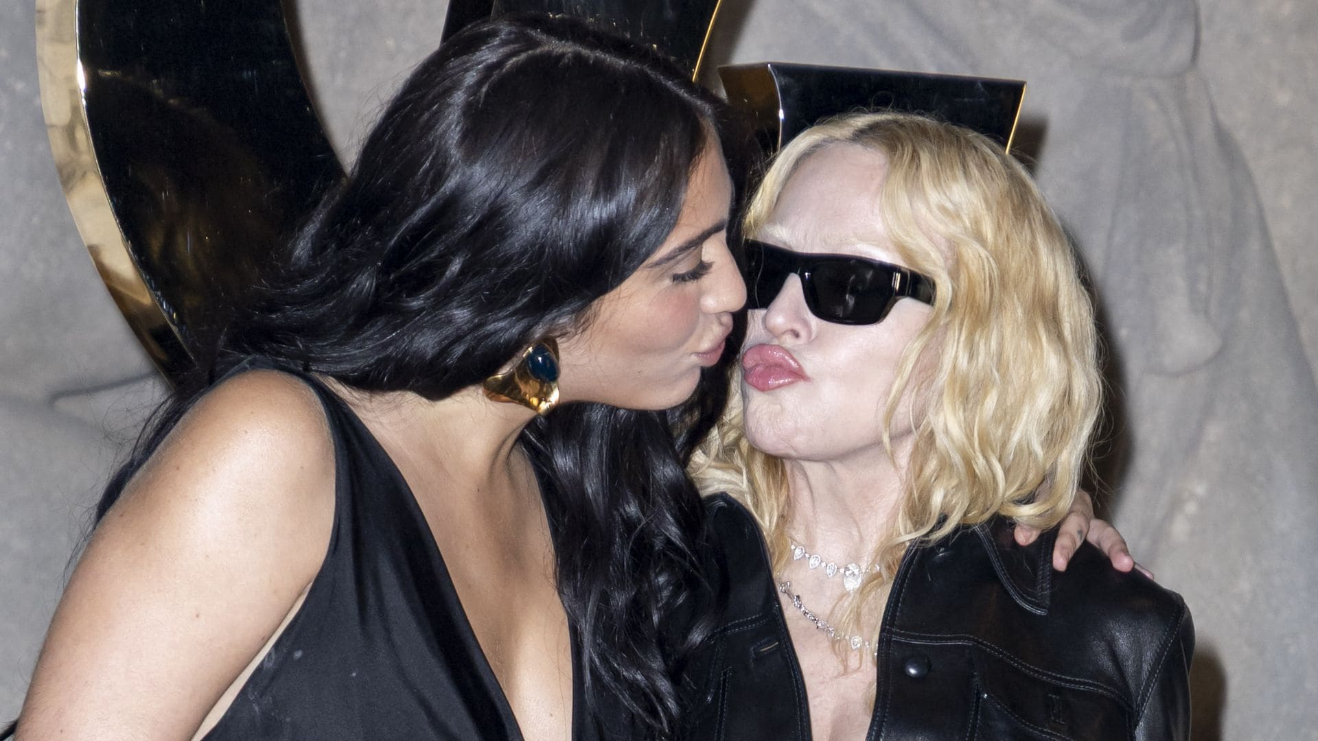 
Madonna attended the Saint Laurent Spring-Summer 2026 show during Paris Fashion Week, posing at the photocall with her daughter Lourdes Leon and Akeem Morris. Madonna wore an all-black outfit featuring a fitted leather jacket with a plunging neckline, a sheer lace skirt revealing lingerie, patent pointed heels, diamond necklaces, dark sunglasses, and a large furry brown handbag. Lourdes Leon matched in a coordinated black look, while Akeem Morris appeared in a dark-toned outfit in line with the evening aesthetic.
***
Madonna asistió al desfile Saint Laurent Primavera-Verano 2026 durante la Semana de la Moda de París y posó en el photocall junto a su hija Lourdes Leon y Akeem Morris. Madonna llevó un conjunto totalmente negro con chaqueta de cuero ajustada y escote pronunciado, falda de encaje transparente que dejaba ver la lencería, tacones de charol puntiagudos, collares de diamantes, gafas de sol oscuras y un bolso marrón peludo de gran tamaño. Lourdes Leon acompañó con un look negro coordinado, mientras que Akeem Morris apareció con un estilismo en tonos oscuros acorde a la estética nocturna.