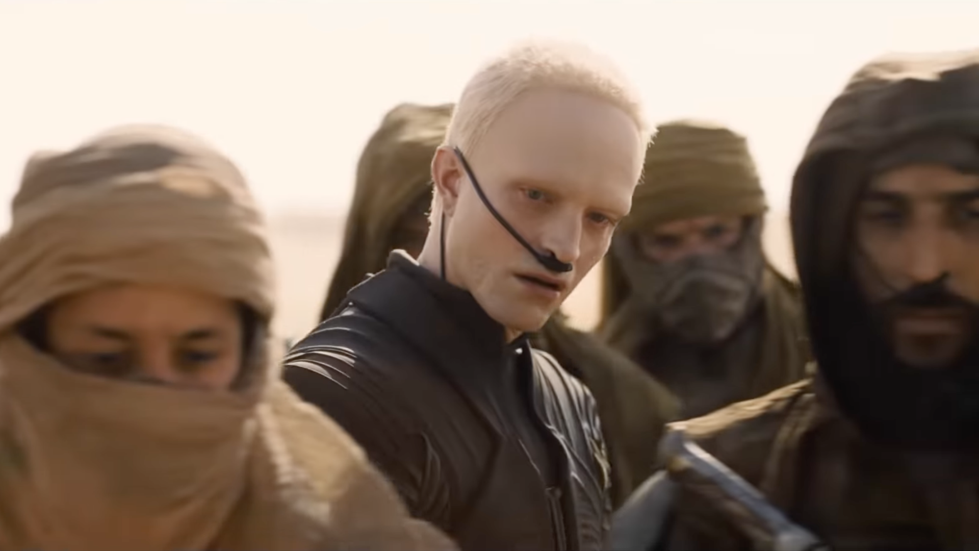 His look, bleached eyebrows, and buzzed blonde hair, is already drawing attention, but it’s the ambiguity of his character that stands out