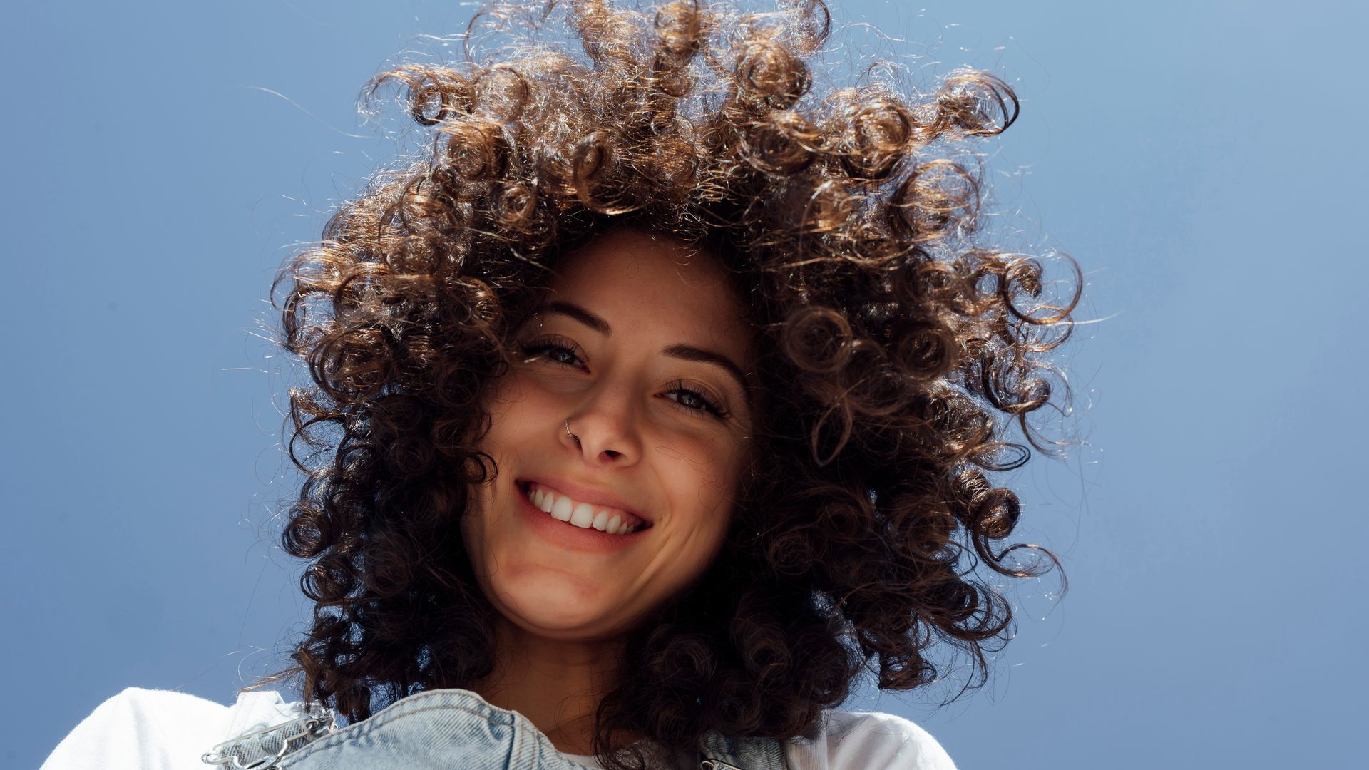https://www.hola.com/us/horizon/landscape/e18273d02668-happy-beautiful-woman-with-curly-hair-under-blue-sky.jpg?im=Resize=(1200)