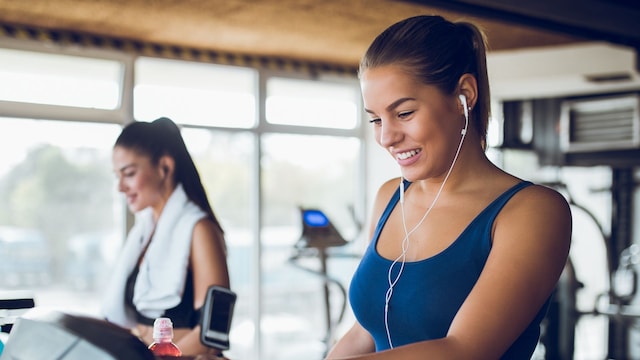 Young woman adjusting speed on a treadmill at gym
