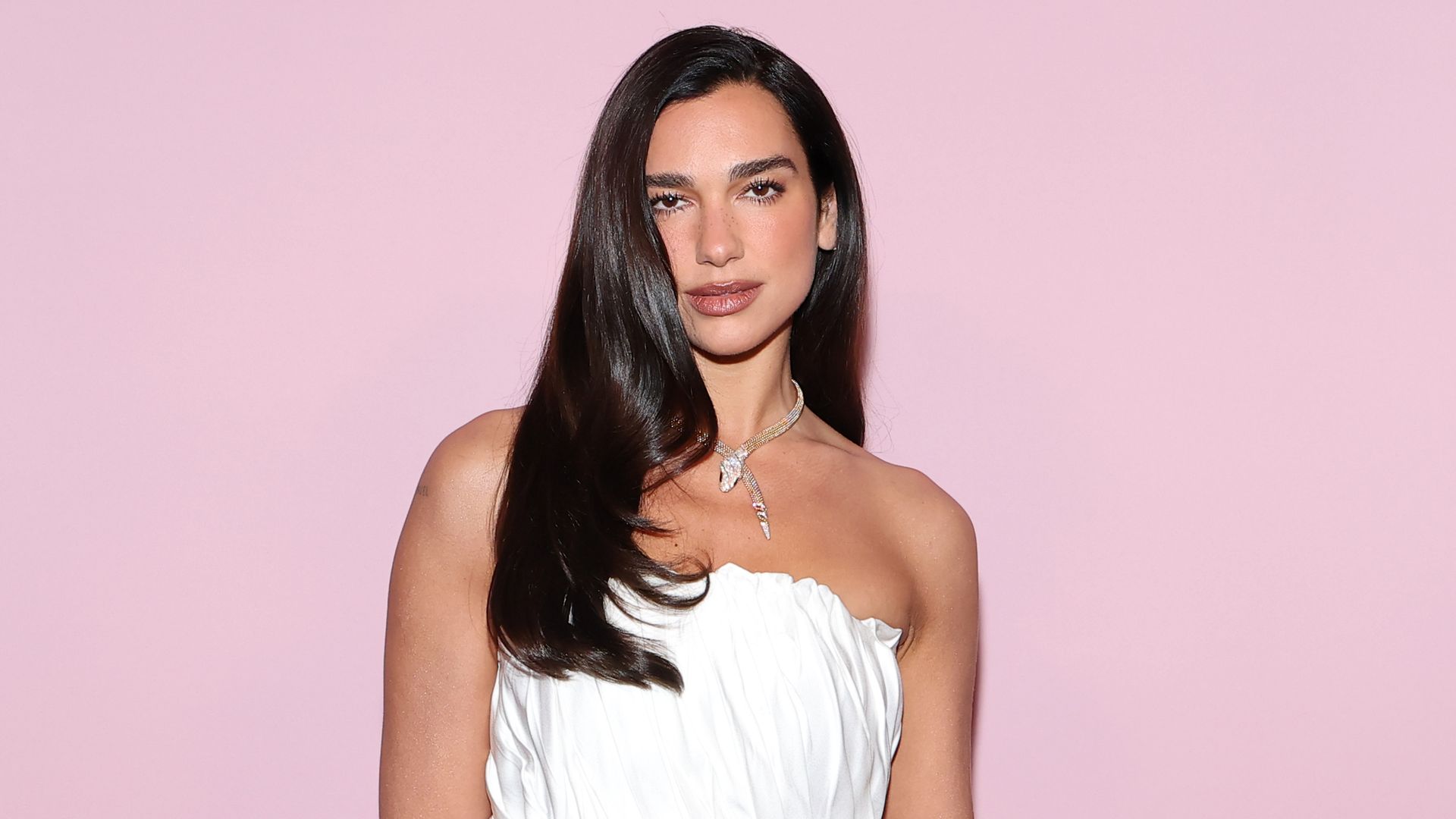 Dua Lipa poses in velvet gown featuring satin bra and lavish diamond and emerald Serpenti necklace