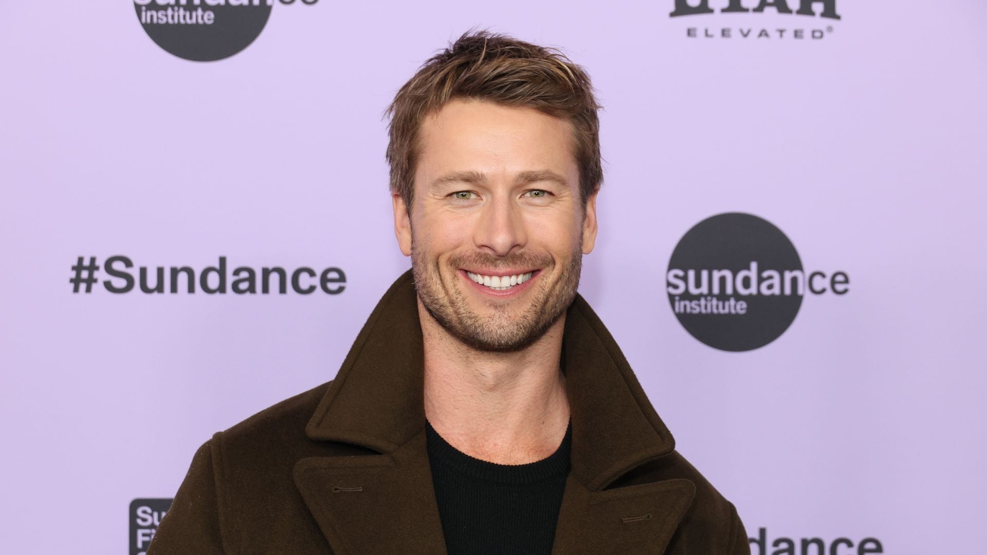 Glen Powell shows off huge biceps while posing with adorable puppy