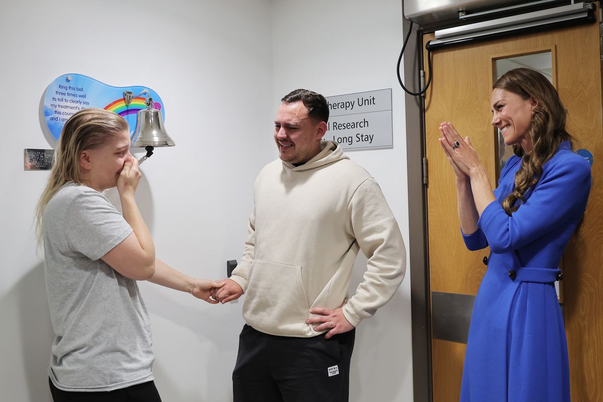 Catherine, Princess of Wales congratulates patient Claire Lorente, and partner Pablo, as she rings the "end of treatment bell" at the Christie cancer care hospital.