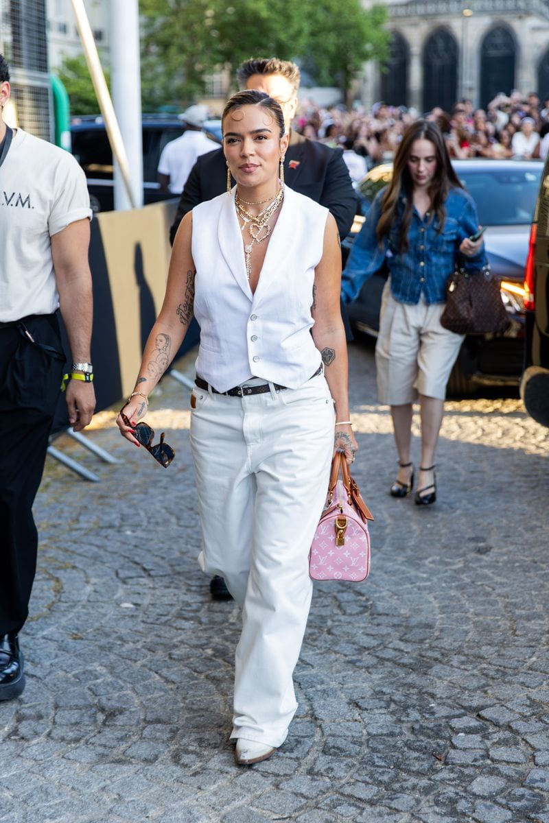  Karol G wears white vest, pants, pink bag attending the Louis Vuitton Menswear Spring/Summer 2026 Fashion Show as part of Paris Fashion Week on June 24, 2025 in Paris, France. (Photo by Christian Vierig/Getty Images)