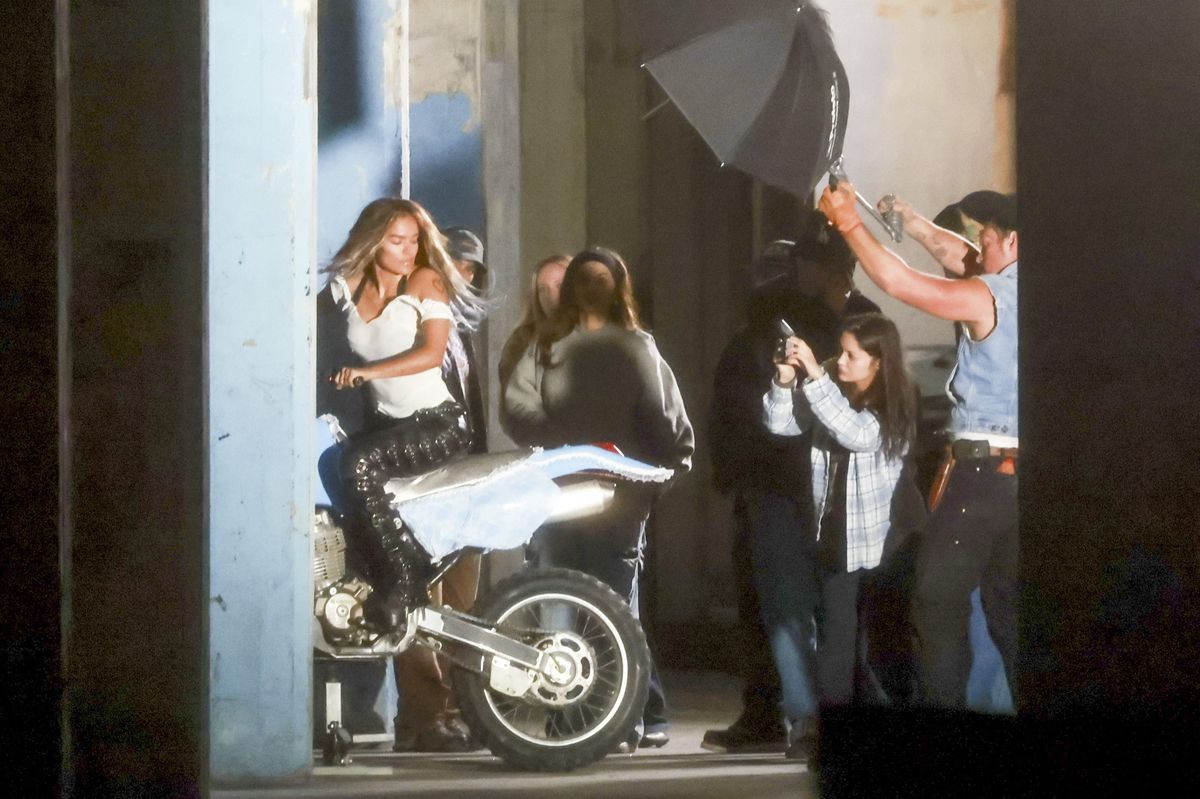 The artist was seen shooting scenes while riding on the back of a motorcycle, holding onto a shirtless male model as production continued in the city.