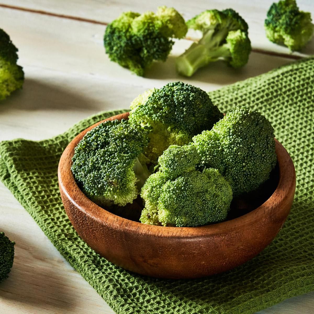 Fresh raw broccoli in bowl on rustic table.