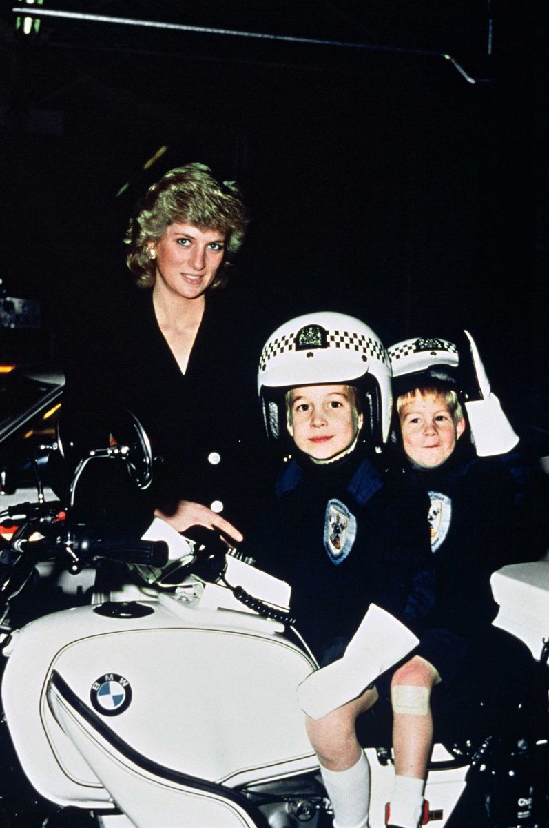Diana, la Princesa de Gales, el Príncipe William, de 5 años, y el Príncipe Harry, de 3 años, usan cascos de policía mientras están sentados en una motocicleta de la policía durante una visita a una estación de policía. 