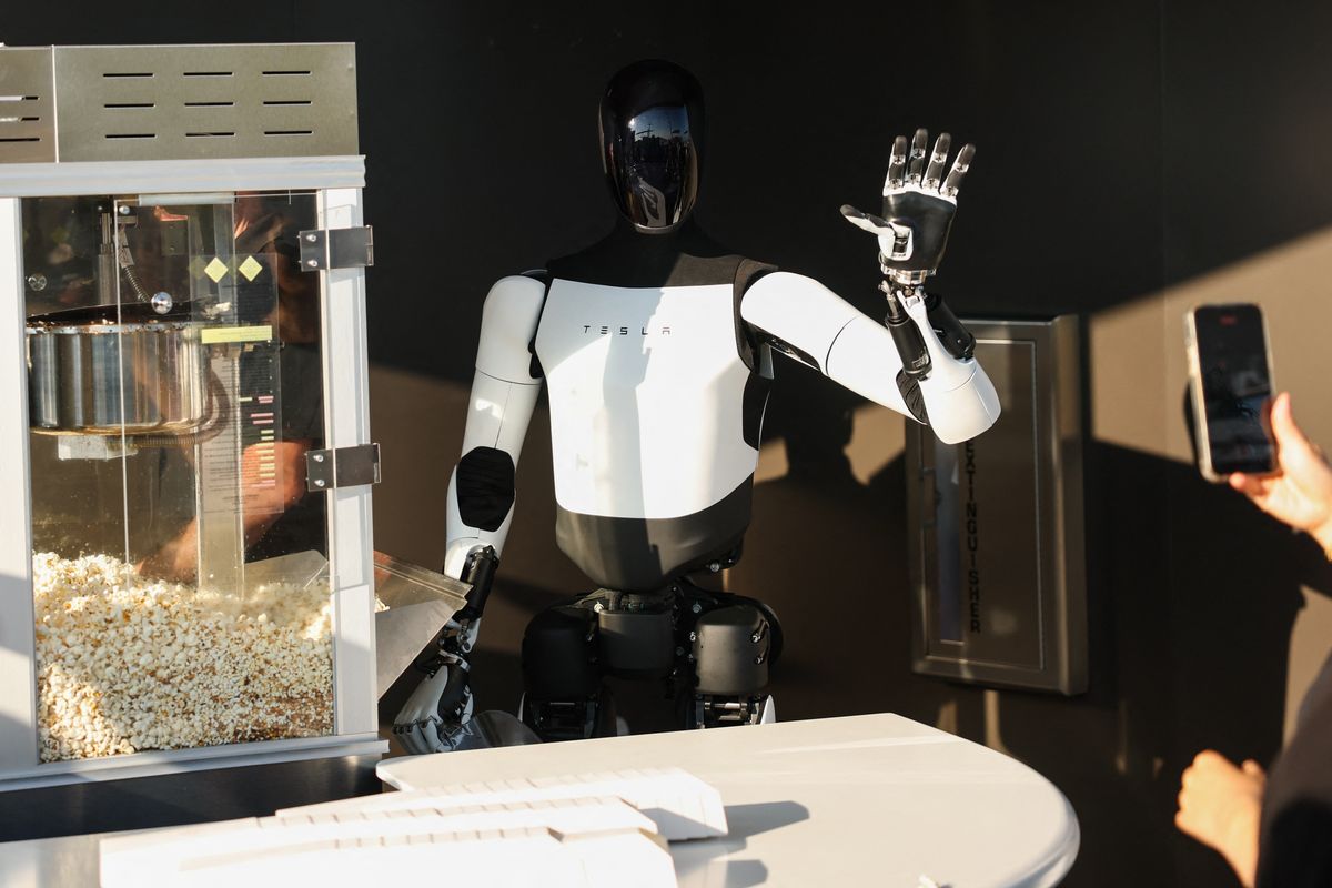 A Tesla Optimus robot scoops popcorn and waves at attendees 