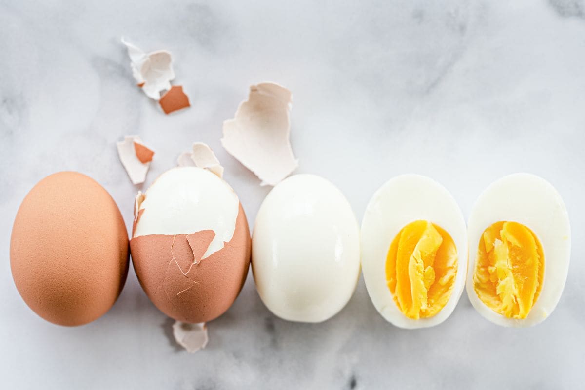 A row of hard boiled eggs showing the order of hard boiling an egg, peeling, and cutting. 