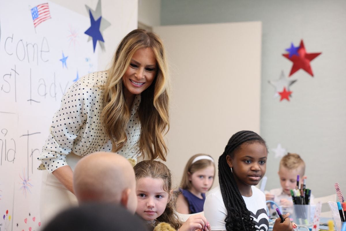 Melania Trump hands a teddy bear to children during a visit to Children's National Hospital 