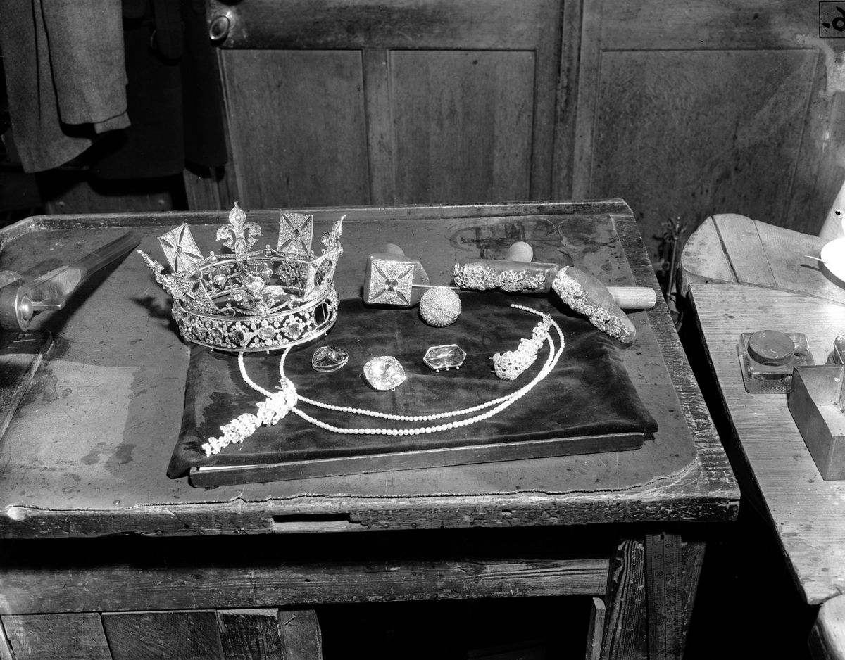 The separate sections of the Imperial State Crown are laid on a table prior to remodelling. The cross pattee surmounts the crown, while the Black Prince's ruby, the Second Star of Africa, and the Stuart sapphire.