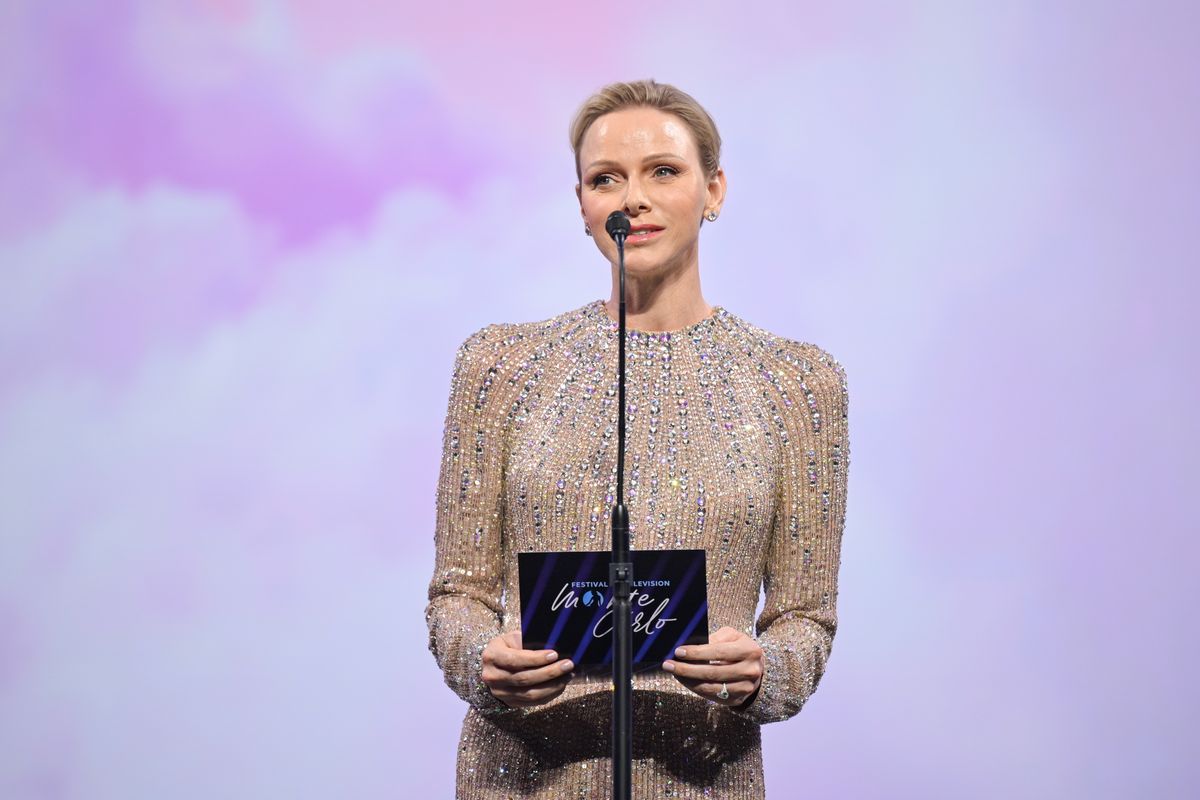 A closer look at Princess Charlene's radiant beauty look, featuring a sleek pixie hairstyle, soft smoky eyes, and timeless diamond stud earrings.