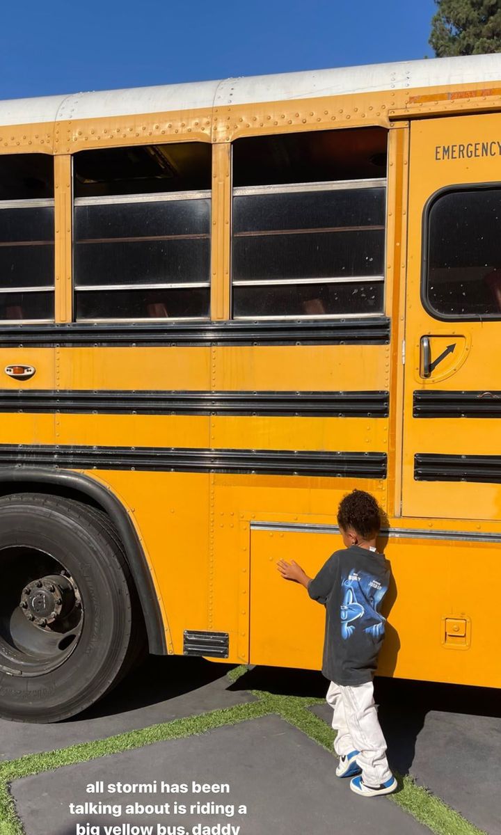 Stormi Webster pretends to ride in a yellow school bus