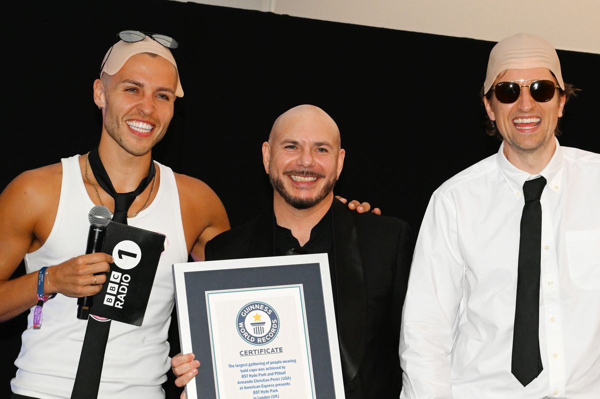 Pitbull (C) is presented with the Guinness World Record title for the 'largest gathering of people wearing bald caps'