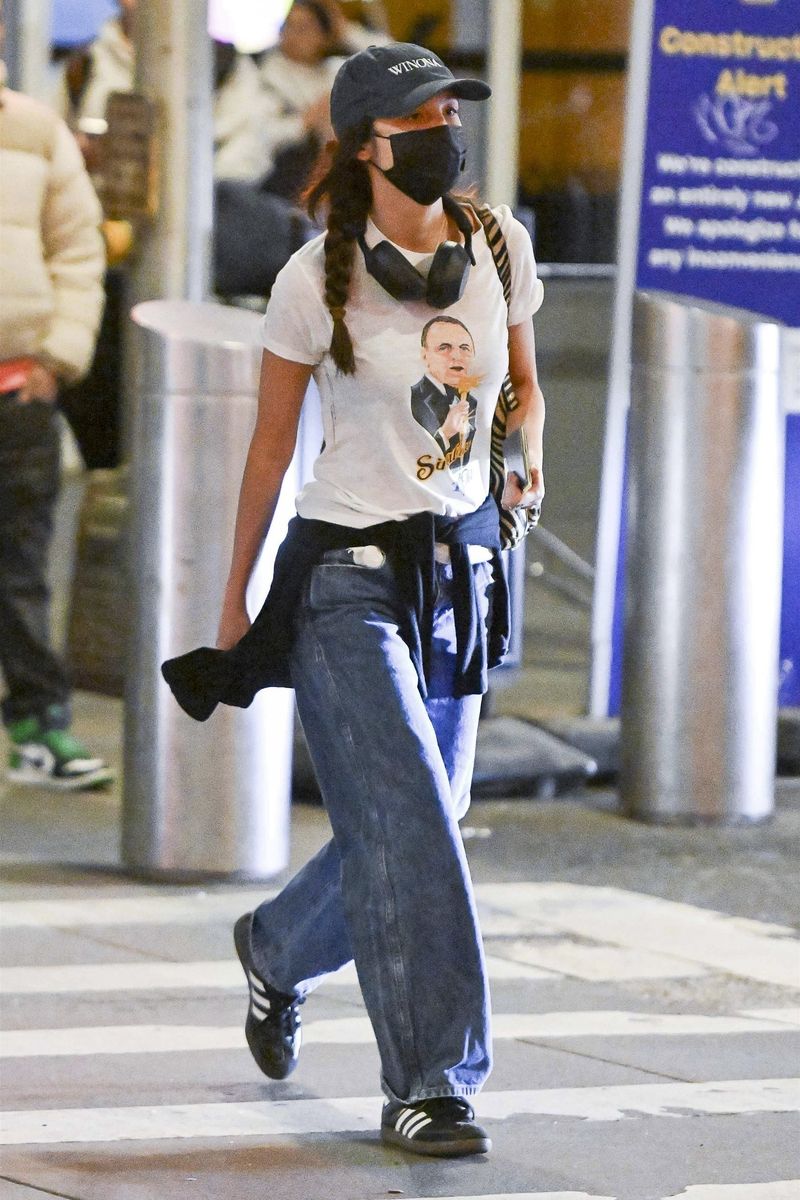 Olivia Rodrigo arriving at JFK airport in NYC wearing a Frank Sinatra 1979 Tour shirt and a Winona hat.