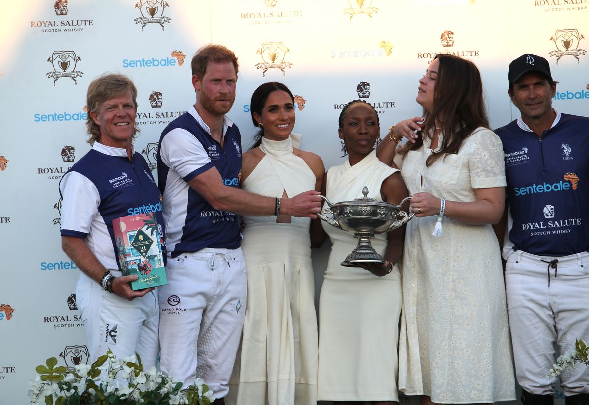 The Duchess of Sussex presents the trophy to her husband, the Duke of Sussex after his team, the Royal Salute Sentebale Team defeated the Grand Champions Team