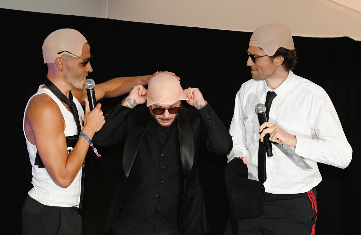 Pitbull (C) is presented with the Guinness World Record title for the 'largest gathering of people wearing bald caps'