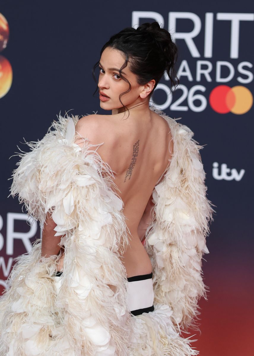 Her look featured a dramatic low-rise black skirt overlaid with cascading ivory feathers, paired with a sculptural top crafted from a feathered boa draped across the chest and shoulders. 