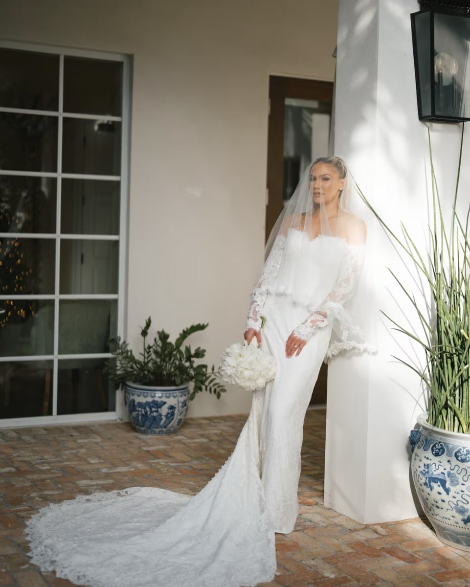 Carrie Lawrence, radiant in a classic white wedding dress with a long train and delicate veil