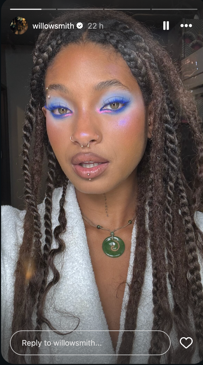 Her makeup features vibrant electric blue and cobalt eyeshadow paired with neon pink liner at the inner corners and lower lash line.
