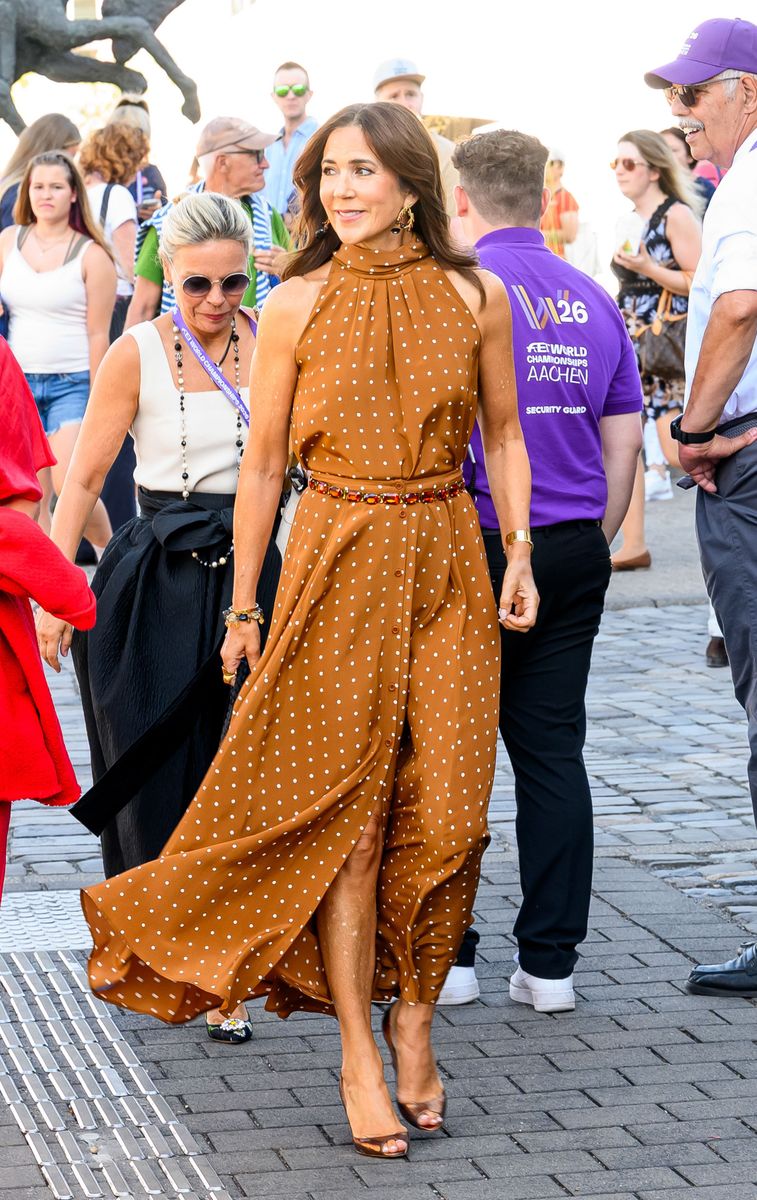 Queen Mary embraces timeless elegance in a flowing caramel polka-dot dress paired with sophisticated accessories.
