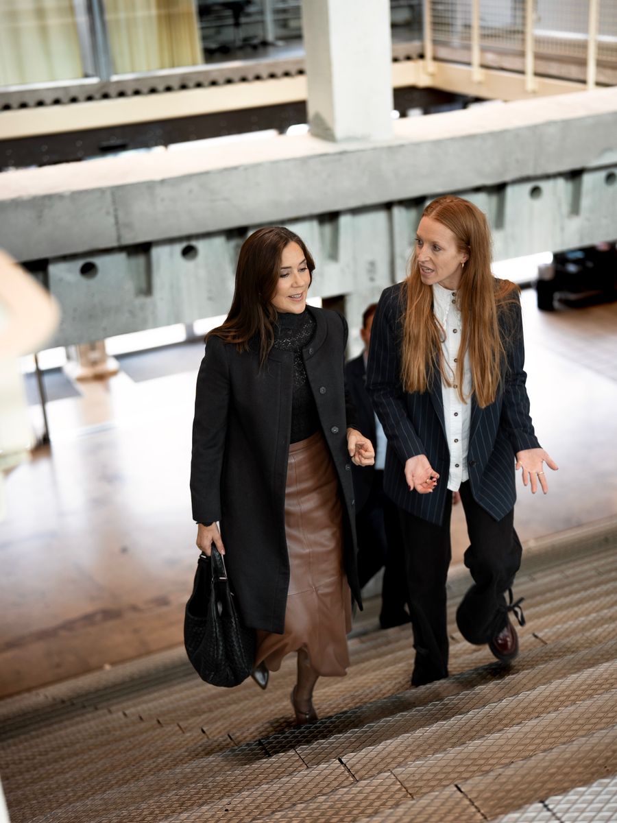 Queen Mary embraced sophisticated fall fashion in Copenhagen, pairing a brown leather midi skirt with a tailored black coat and matching boots.