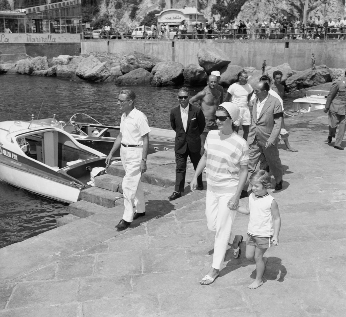 A barefoot Caroline and her mother Mrs. Jacqueline Kennedy stroll along a pier in Amalfi here, to board the yacht of Italian industrialist Gianni Agnelli. 
