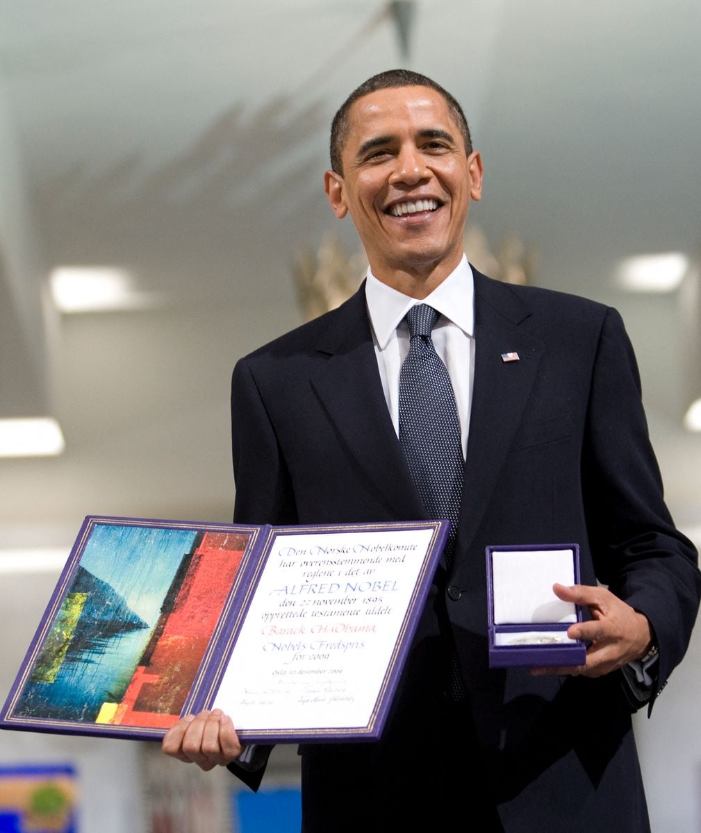 TOPSHOT - Nobel peace Prize laureate and US President Barack Obama poses with his medal and diploma during the Nobel Peace prize award ceremony at the City Hall in Oslo on December 10, 2009. The president faces a tricky task of reconciling the revered honor with his decision just last week to send 30,000 troops to escalate the war in Afghanistan, a move which tripled the US force there since he took office.    AFP PHOTO/Bjorn Sigurdson / POOL (Photo by BJORN SIGURDSON / POOL / AFP) (Photo by BJORN SIGURDSON/POOL/AFP via Getty Images)
