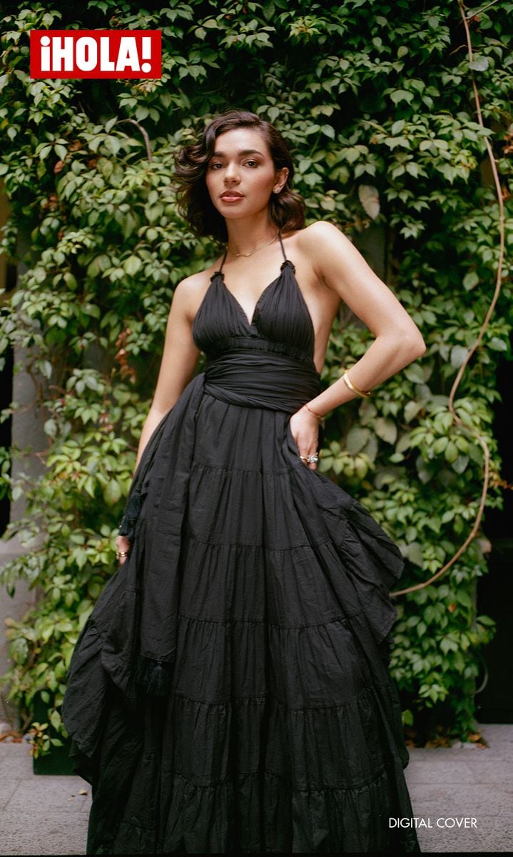 Paulina wears a black linen dress with seams on the skirt and a V-neckline, a piece designed by Erika Peña