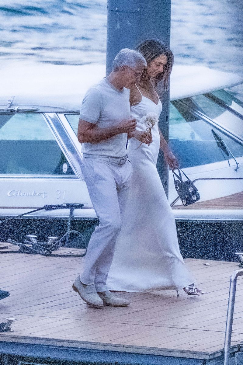 Carrying a delicate arrangement of white flowers, Amal brought bridal-inspired glamour to the romantic lakeside outing.