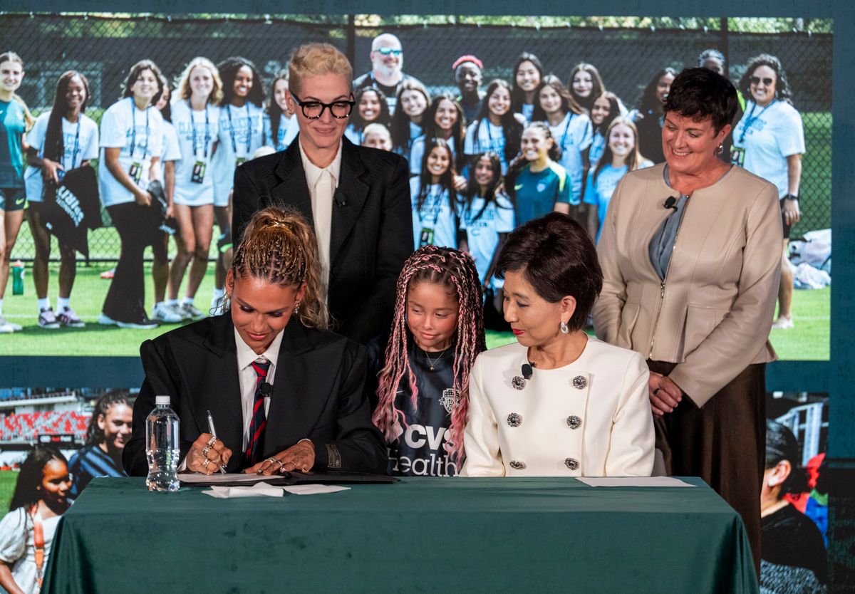 Trinity Rodman of the United States re-signs with her club team, the Washington Spirit,  alongside club owner Michele Kang.