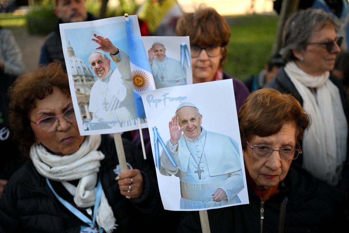 Faithful Catholics hold posters with images of Pope Francis in front of the Cathedral in Buenos Aires on April 26, 2025, as his funeral takes place in Vatican. 